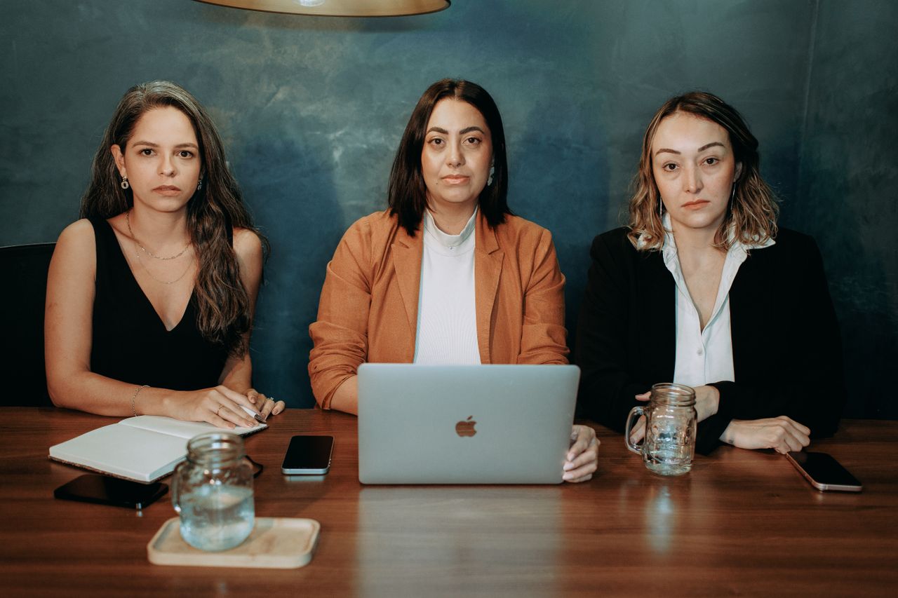The Art of Drawing Readers In: Your attractive post title goes here Three serious women in formal wear at a business meeting with laptops and notebooks.